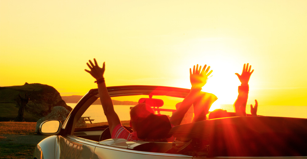 Sunset watching from vehicle with people with arms up