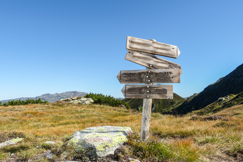 wooden sign with arrow pointing different directions on a mountain top